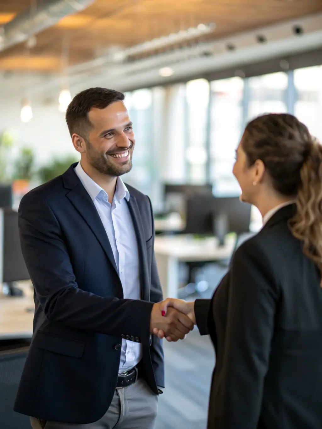 A satisfied client shaking hands with an R&R Construction project manager in a newly renovated office space, highlighting the company's dedication to client satisfaction.